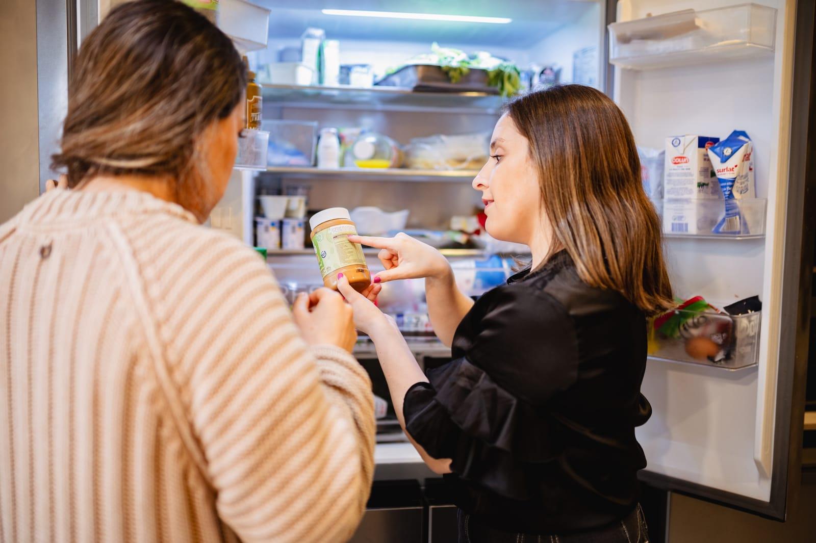 Nutricionista de NutriFam revisando productos del refrigerador con una clienta